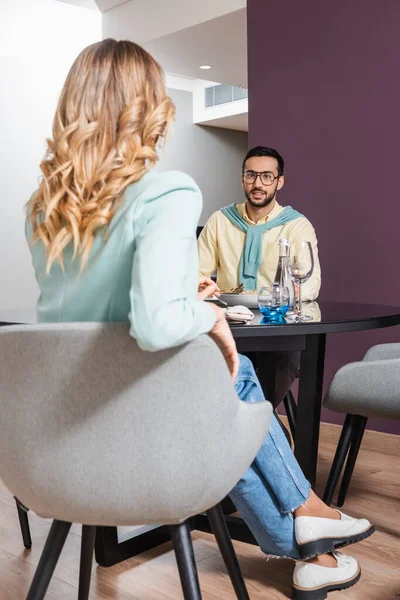 Smiling arabian man having dinner with girlfriend on blurred foreground in hotel — Stock Photo