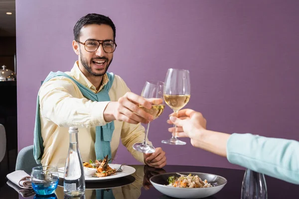 Cheerful arabian man clinking wine with girlfriend near dinner in hotel room — Stock Photo