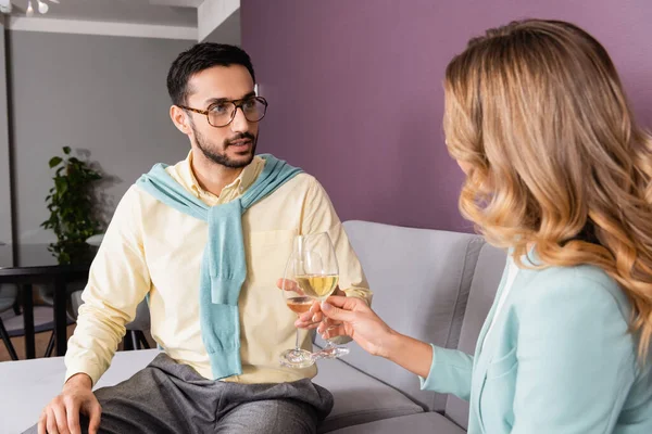 Arabe homme tenant verre de vin près de petite amie sur le premier plan flou à l'hôtel — Photo de stock