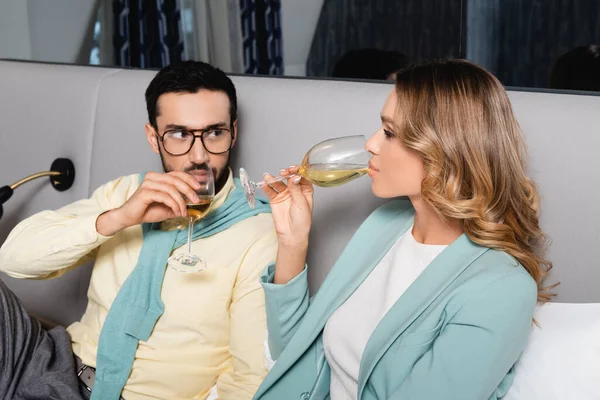 Young interracial couple drinking wine on hotel bed — Stock Photo