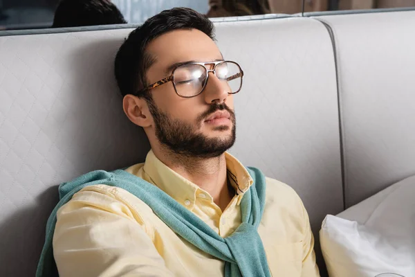 Muslim man in eyeglasses sitting on bed in hotel — Stock Photo