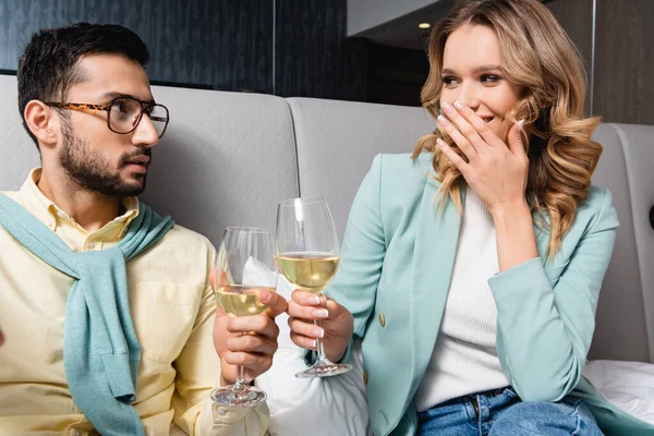 Cheerful woman toasting wine with Muslim boyfriend in hotel — Stock Photo