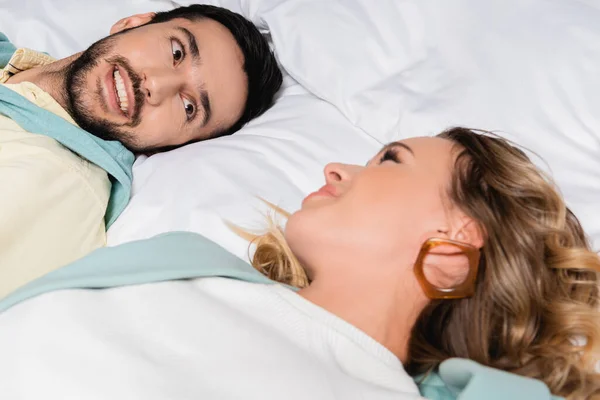 Hombre musulmán sonriendo a su novia en primer plano borroso en la cama del hotel - foto de stock