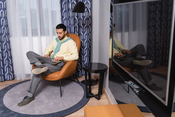 Freelance musulman utilisant un ordinateur portable dans la chambre d'hôtel moderne — Photo de stock