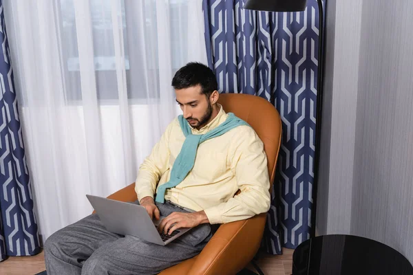 Joven musulmán freelancer utilizando el ordenador portátil en la habitación de hotel - foto de stock