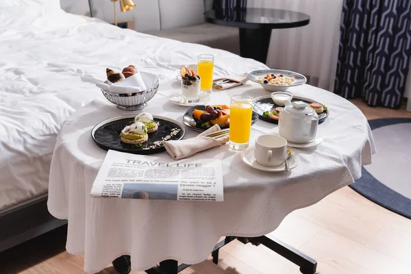 Periódico cerca del desayuno y bebidas en la mesa en la habitación del hotel - foto de stock