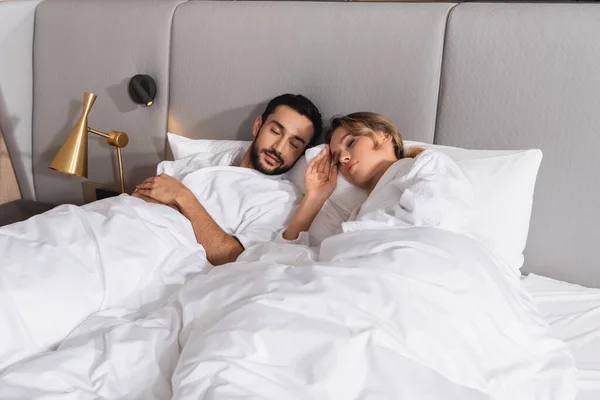 Young interracial couple sleeping on hotel bed — Stock Photo