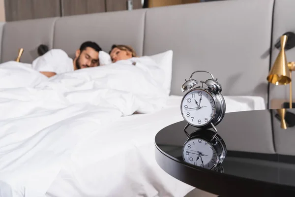 Réveil sur table et couchage interracial couple sur fond flou à l'hôtel — Photo de stock