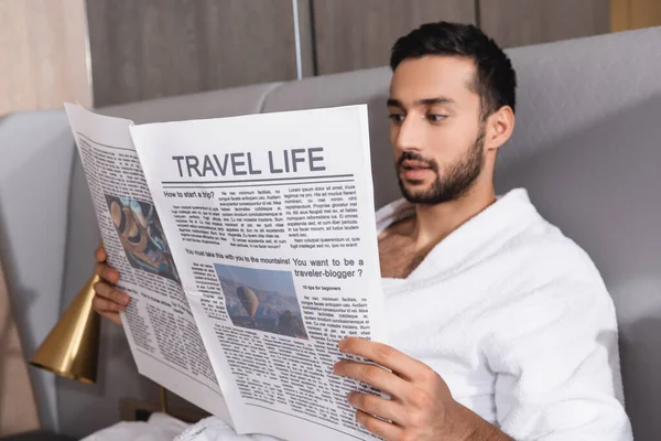 Travel life lettering on newspaper in hands of arabian man in bathrobe in hotel — Stock Photo