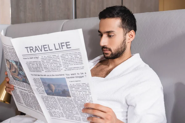 Homem árabe lendo jornal com vida de viagem em primeiro plano desfocado no hotel — Fotografia de Stock