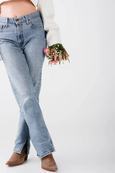 Vista cortada de mulher em jeans e flores na manga de jaqueta em fundo cinza — Fotografia de Stock