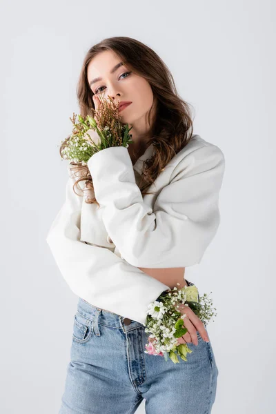 Young model with flowers in sleeves of jacket posing isolated on grey — Stock Photo