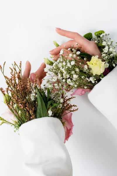 Vista ritagliata di mani femminili con fiori in maniche di giacca su sfondo grigio — Foto stock
