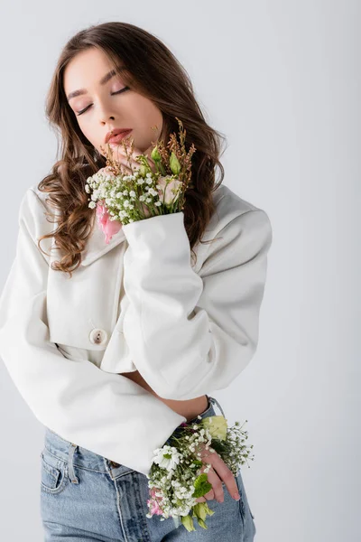 Woman with different flowers in sleeves of jacket posing isolated on grey — Stock Photo