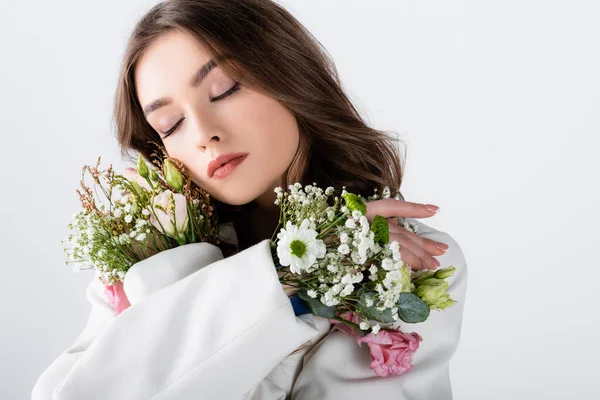 Junge Frau mit Blumen in den Ärmeln der Jacke stehend mit geschlossenen Augen isoliert auf grau — Stockfoto