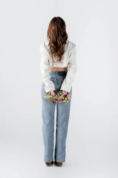Visão traseira da mulher com flores em mangas de jaqueta em pé sobre fundo cinza — Fotografia de Stock