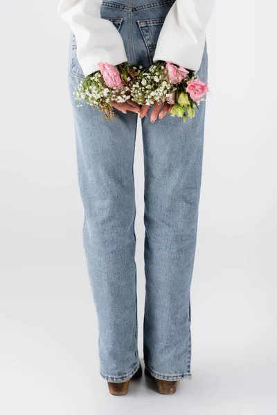 Vista cortada de mulher em jeans e flores em casaco em cinza — Fotografia de Stock