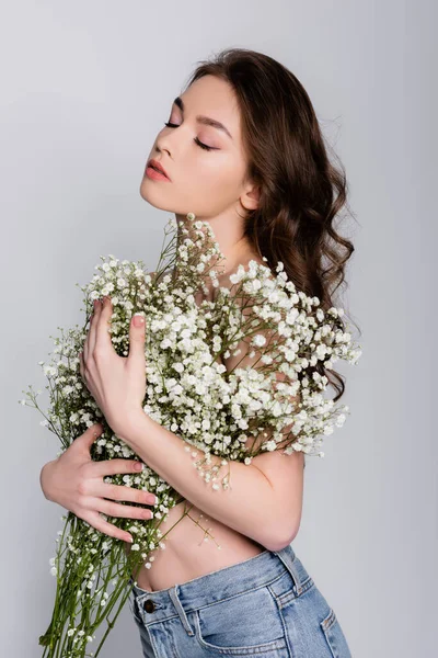 Модель без сорочки, що тримає квіти біля грудей ізольовані на сірому — стокове фото