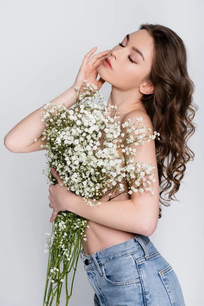 Mulher morena sem camisa posando com flores isoladas em cinza — Fotografia de Stock