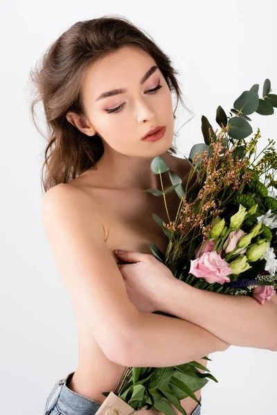 Mujer joven sin camisa abrazando flores aisladas en gris - foto de stock