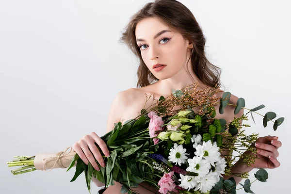 Woman with naked shoulders holding flowers and looking at camera isolated on grey — Stock Photo