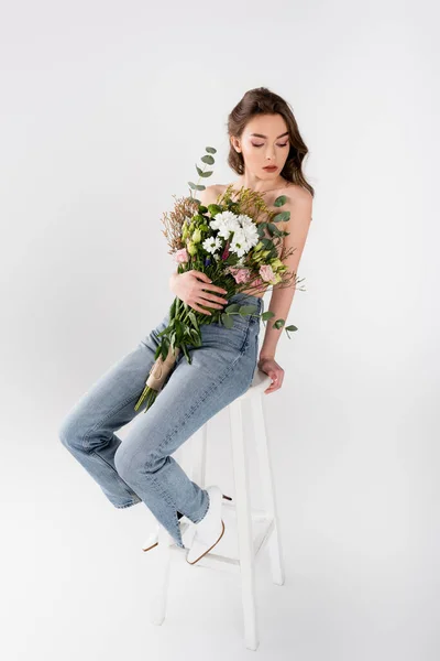 Modello senza maglietta con bouquet seduta su sedia isolata su grigio — Foto stock