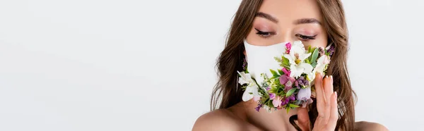 Giovane donna con mano vicino a fiori sulla maschera medica isolata su grigio, striscione — Foto stock