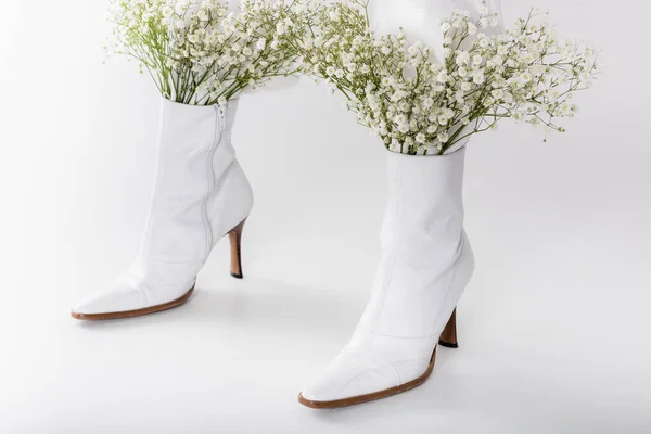 Cropped view of legs of woman in white shoes with small flowers on grey background — Stock Photo