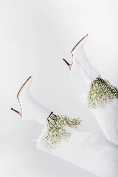Vista recortada de flores de aliento de bebé en zapatos de mujer aislados en gris - foto de stock