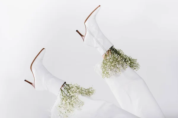 Teilansicht kleiner weißer Blumen in Schuhen von Frau isoliert auf grau — Stockfoto
