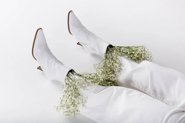 Ausgeschnittene Ansicht der Beine einer Frau in weißen Schuhen und Hosen mit Blumen auf grauem Hintergrund — Stockfoto