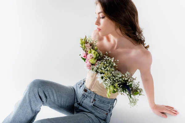 Giovane modella posa con fiori in camicetta su sfondo grigio — Foto stock