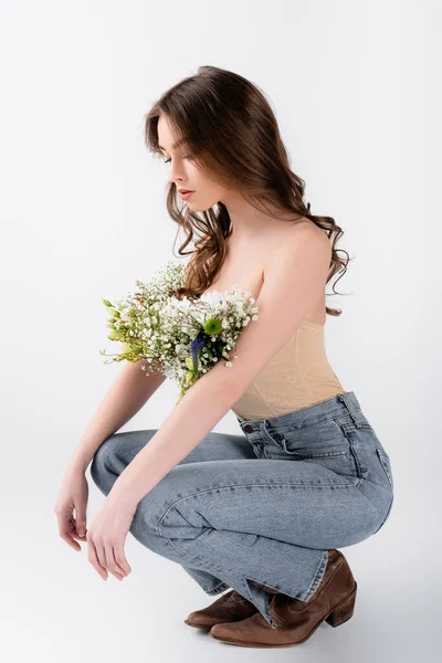 Modello riccio guardando i fiori in camicetta su sfondo grigio — Foto stock