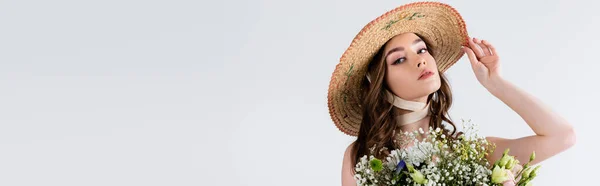 Donna in cappello di paglia guardando la macchina fotografica vicino a fiori isolati su grigio, banner — Foto stock