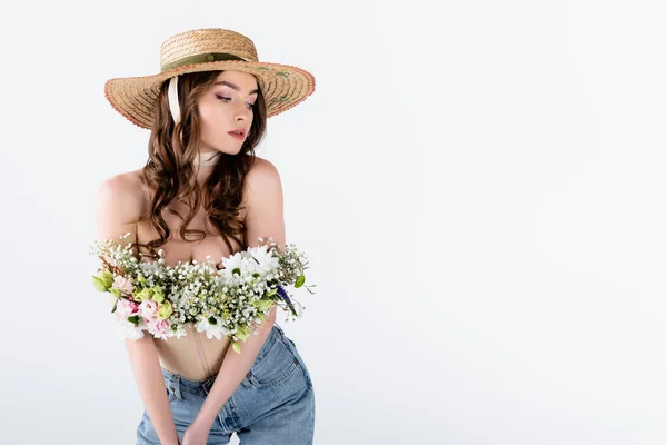 Модель з квітами в блузці позує в сонячному капелюсі ізольовано на сірому — стокове фото