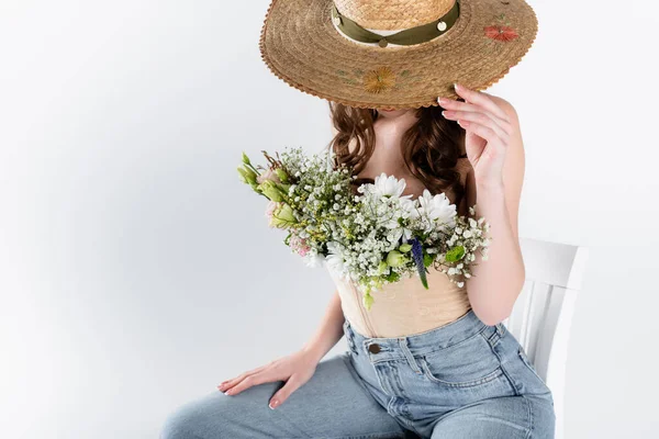 Woman with flowers in blouse covering face with sun hat isolated on grey — Stock Photo