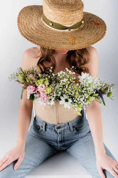 Квіти в блузці жінки в сонячному капелюсі ізольовані на сірому — стокове фото