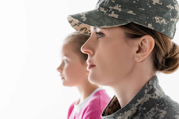 Vista lateral del soldado mirando hacia otro lado cerca de su hija sobre fondo borroso aislado en blanco - foto de stock