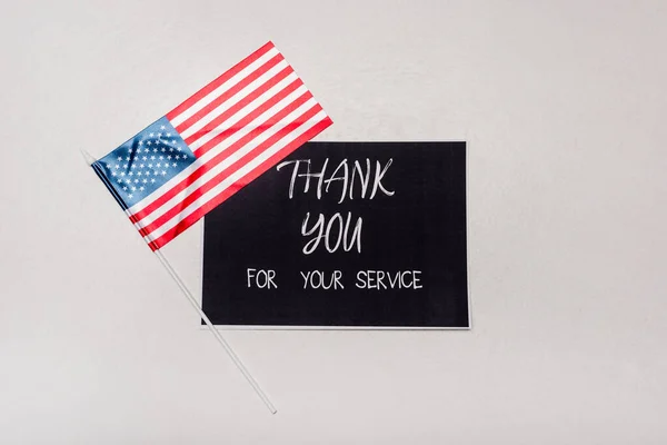 Top view of American flag near card with thank you for your service lettering on grey background — Fotografia de Stock