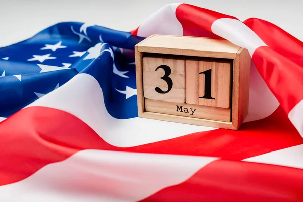 Vista de cerca del calendario con 31 de mayo de fecha en bandera americana en primer plano borroso sobre fondo gris - foto de stock