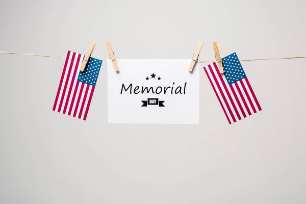 Tarjeta con letras del día conmemorativo y banderas americanas en cuerda aislada en gris - foto de stock