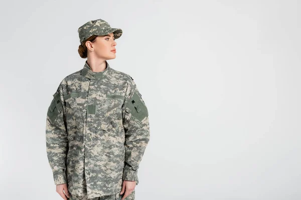 Soldier in cap and uniform looking away isolated on grey — Stock Photo
