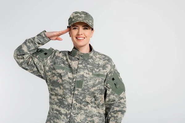 Woman in camouflage clothes saluting isolated on grey — Stock Photo