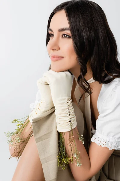 Dreamy young woman in gloves with flowers looking away isolated on white — Stock Photo