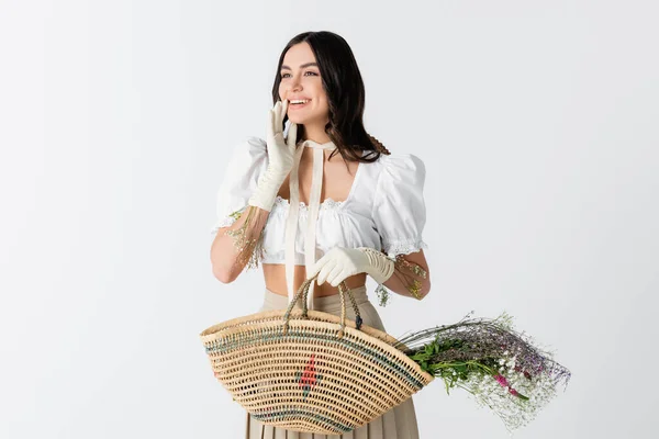 Heureuse jeune femme tenant sac de paille avec des fleurs de printemps isolé sur blanc — Photo de stock