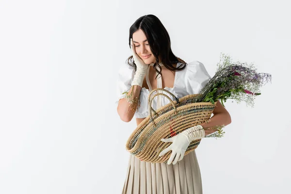 Чувственная молодая женщина держит соломенный мешок с весенними цветами изолированы на белом — стоковое фото