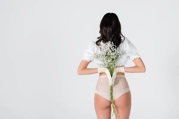 Vue arrière de la femme brune en gants et culotte avec des fleurs en fleurs posant isolé sur blanc — Photo de stock