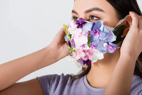 Mujer joven con máscara médica con flores en flor aisladas en blanco - foto de stock