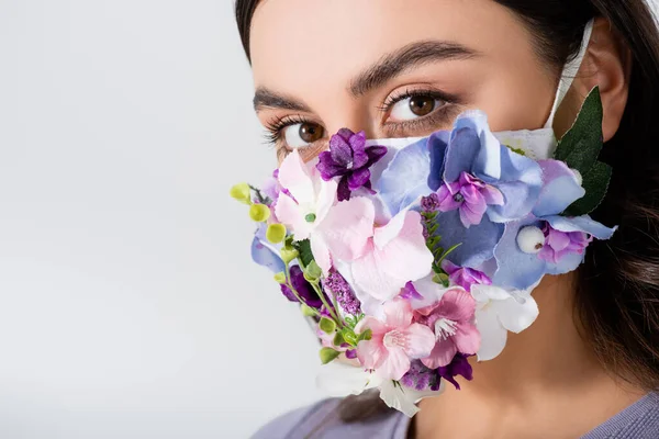 Mujer joven en máscara médica con flores en flor aisladas en blanco - foto de stock