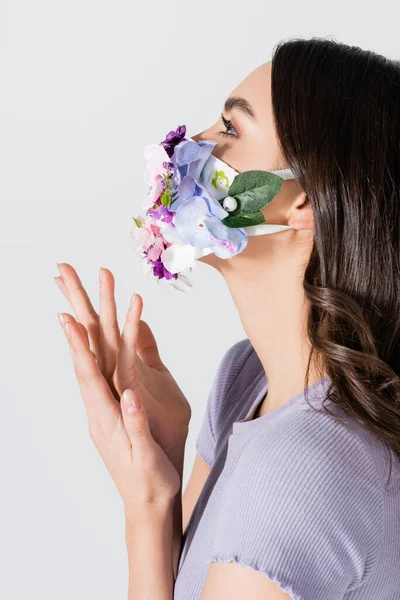 Mujer joven en máscara médica con flores gesto aislado en blanco - foto de stock